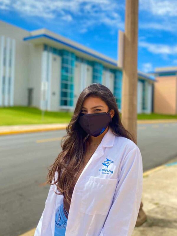 joven con bata de laboratorio blanca y logo de UPR Aguadilla