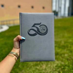 libreta encuadernada color gris con el logo representativo del 50 aniversario de UPR Aguadilla