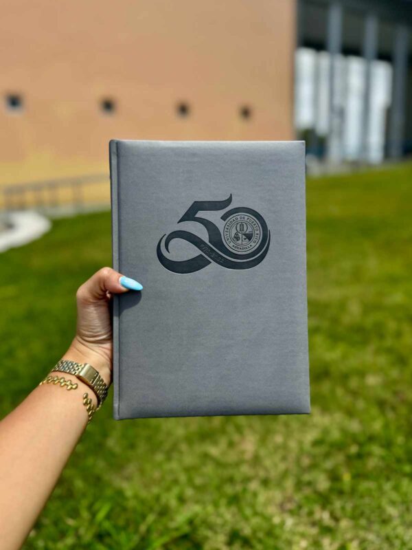 libreta encuadernada color gris con el logo representativo del 50 aniversario de UPR Aguadilla