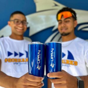 jóvenes sosteniendo dos vasos insulados color azul con logo UPR Aguadilla