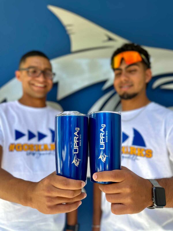 jóvenes sosteniendo dos vasos insulados color azul con logo UPR Aguadilla