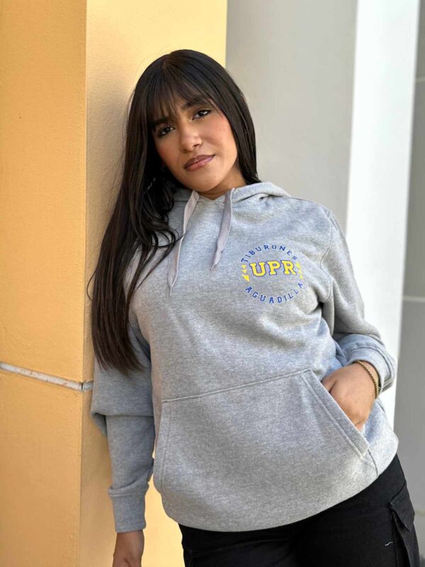 joven mujer con sudadera color gris con logo de UPR Aguadilla