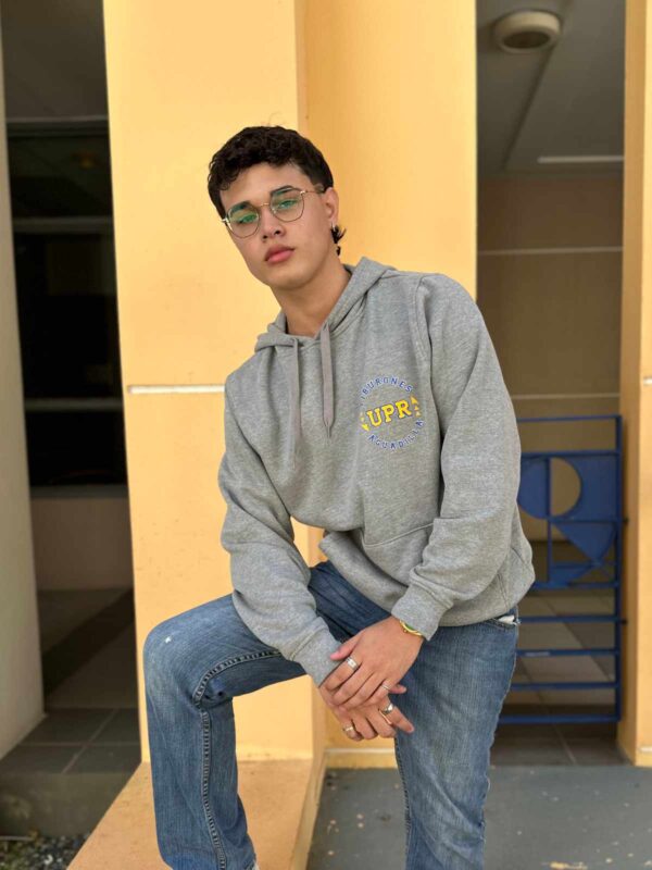 joven varón con sudadera gris con logo UPR Aguadilla