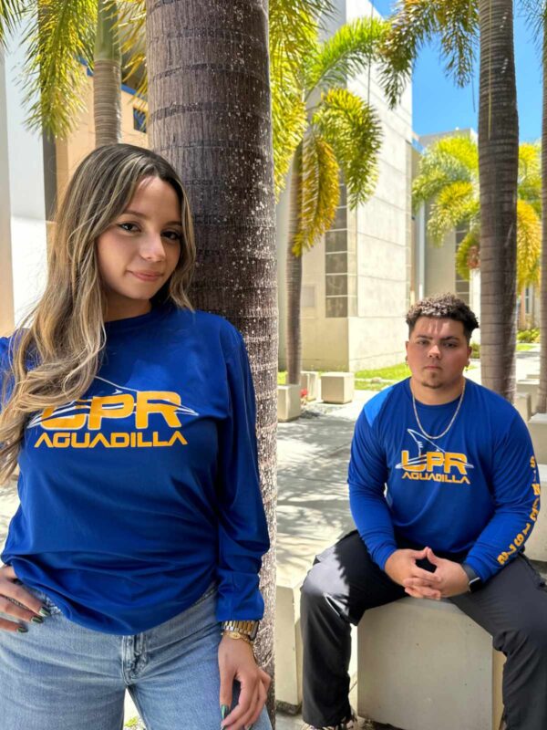 pareja de jóvenes modelando playera azul con logo UPR Aguadilla