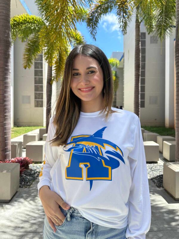 joven dama modelando playera blanca con logo de tiburón y letra A en azul