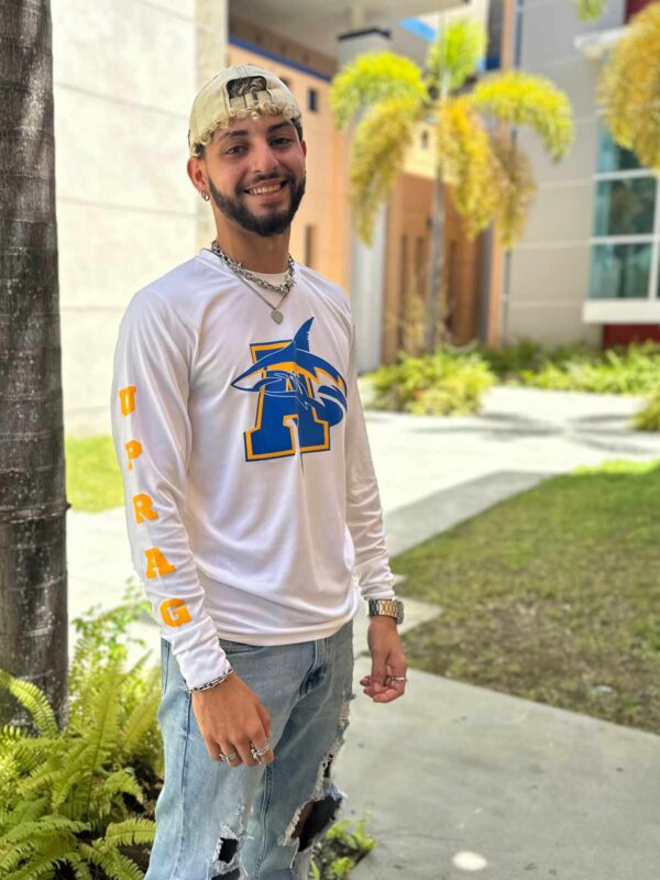 joven varón modelando playera blanco con logo de tiburón y letra A en azul en la manga