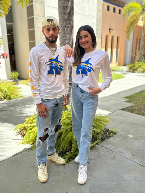 pareja de jóvenes modelando playera blanca con logo de tiburón y letra A en azul y amarillo