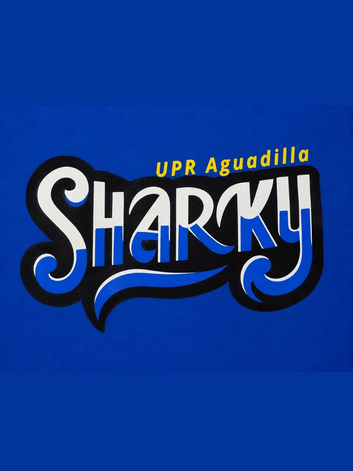 Detalle de estampado de Sharky UPR Aguadilla, la palabra Sharky en color blanco y azul con fondo negro