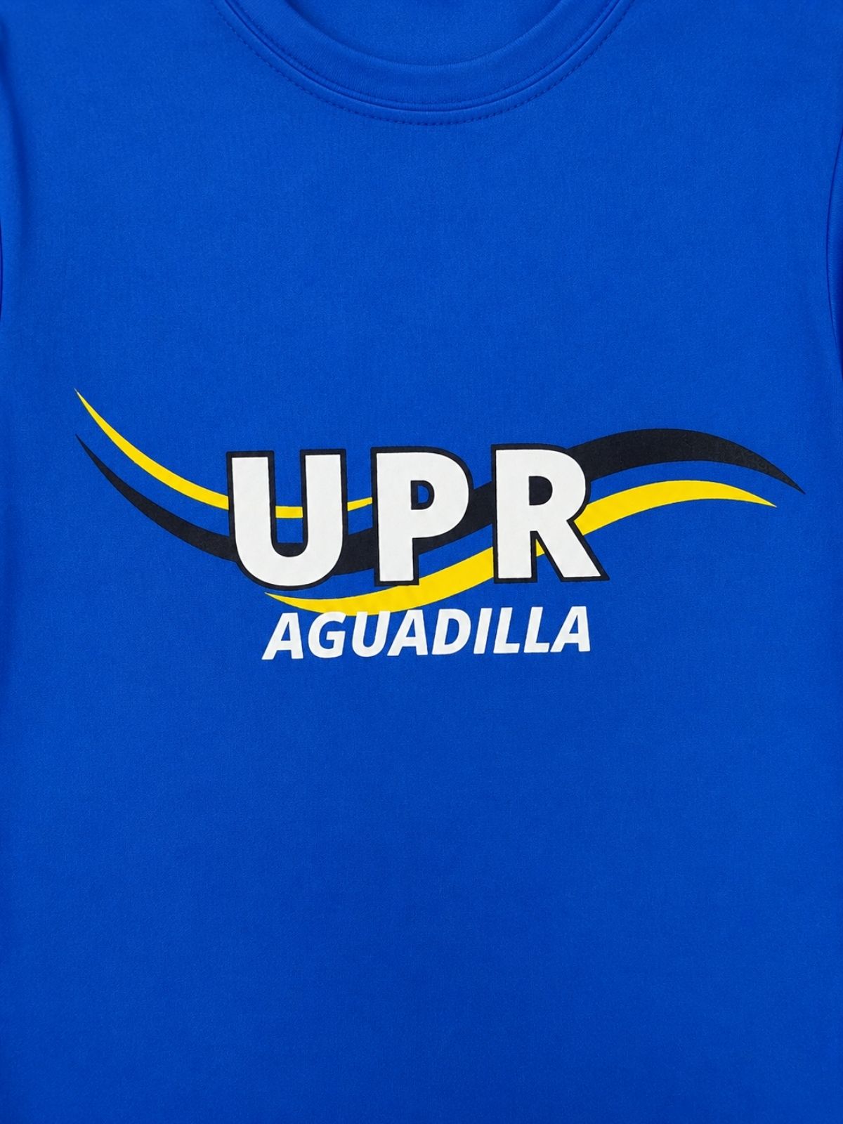 Detalle de estampado de UPR Aguadilla y ondas en el fondo en blanco, amarillo y negro en tela azul royal