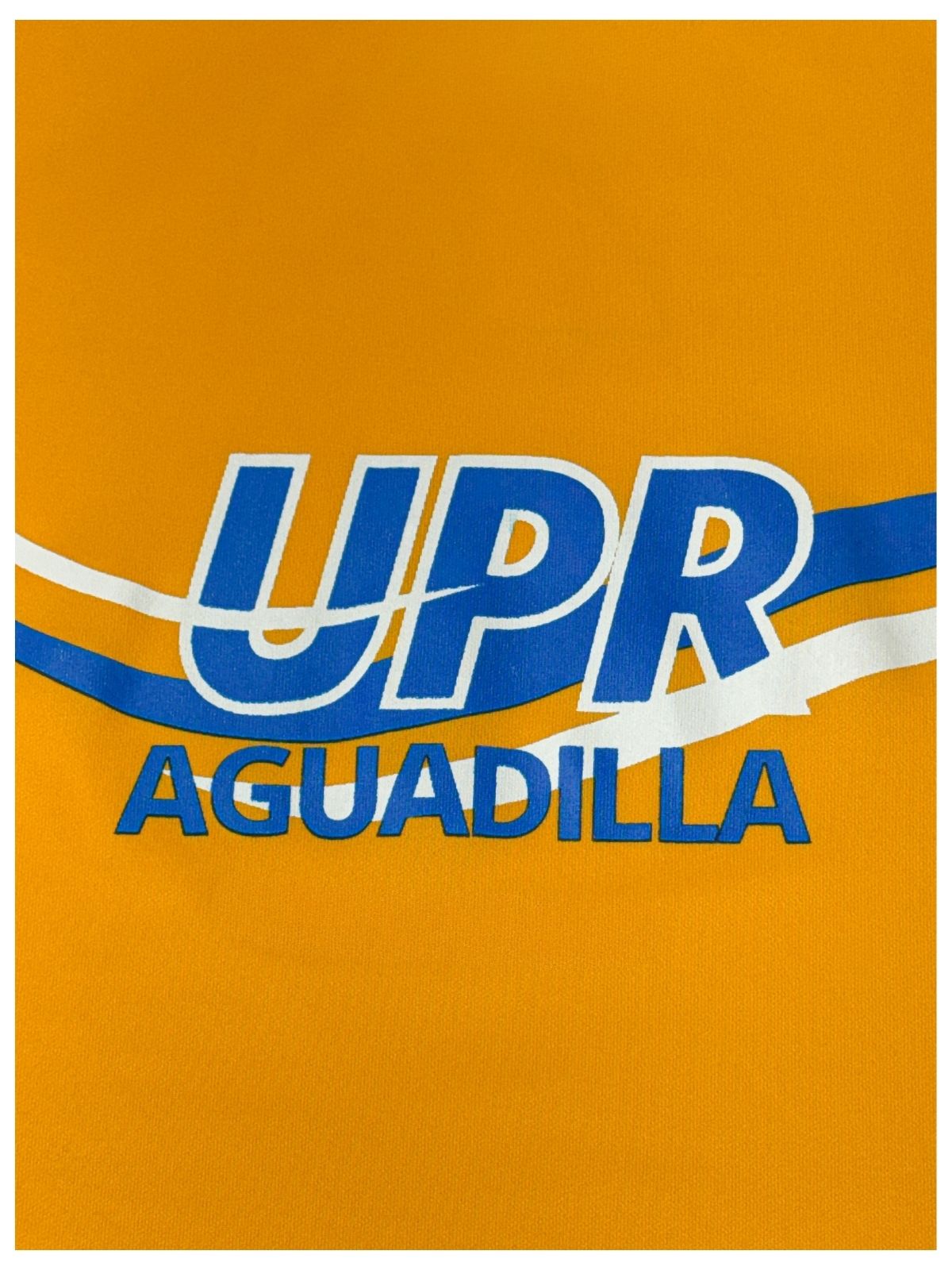 Detalle de estampado de UPR Aguadilla y ondas en el fondo en azul royal y blanco sobre tela amarilla
