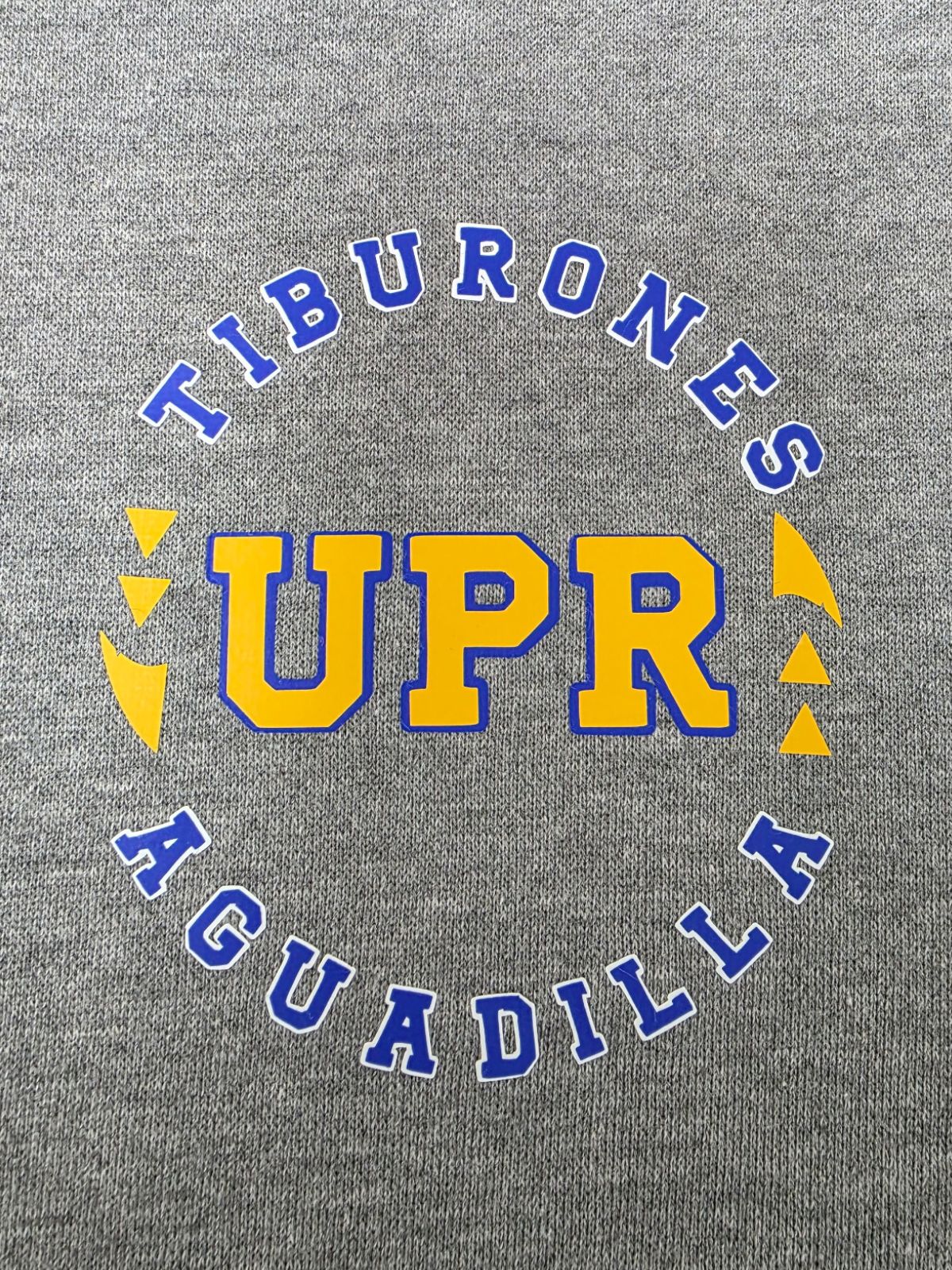 Estampado redondo Tiburones UPR Aguadilla en azul royal y amarillo sobre tela gris
